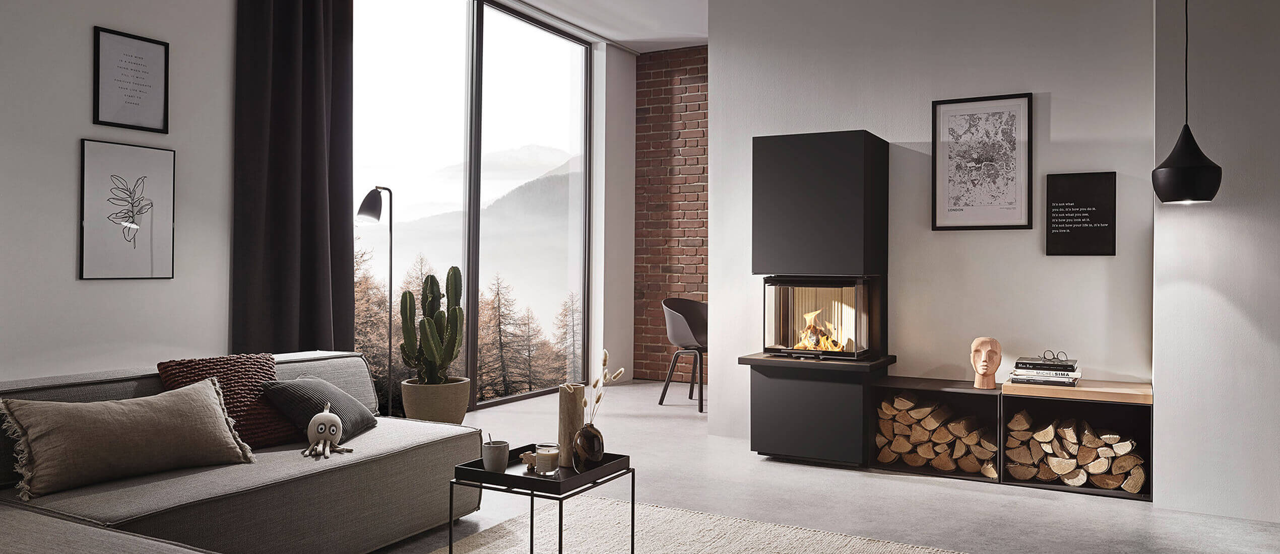 Helle Wohnlandschaft mit einem schwarzen Kaminmöbel und brennendem Feuer. Holzvorrat im Kaminmöbel integriert.